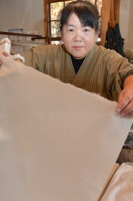 水を絞った紙を持ち上げる福田博子さん