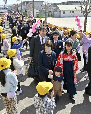 花道で在校生の見送りを受け、学びやを後にする卒業生＝１５日午前１１時２５分、下野市緑３丁目