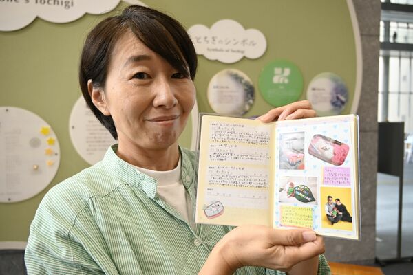 自身のリトルベビーハンドブックを手に写真展をＰＲする小林代表