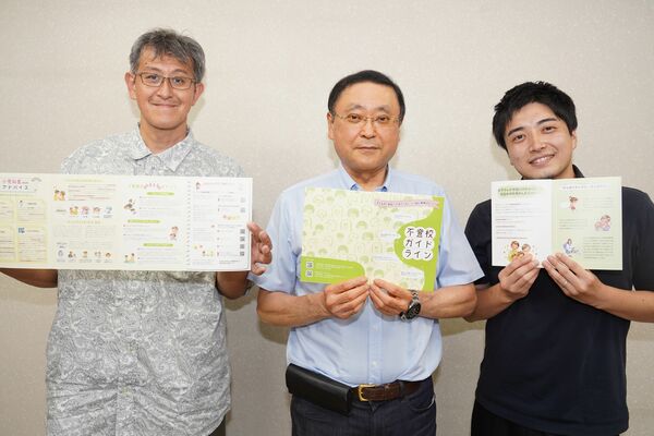 完成した「不登校ガイドライン」を手にする松本会長（中央）と土橋代表理事（右）ら＝宇都宮市内
