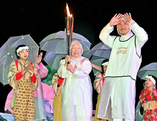 聖火リレーをやり遂げ、笑顔でトーチを掲げる箱石さん（中央）＝2021年３月28日、那須烏山市金井２丁目、杉浦崇仁撮影