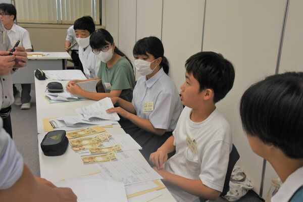 架空の事件の証拠品を見ながら質問を考える中学生たち＝９日午前、宇都宮市明保野町