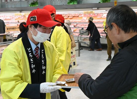 買い物客にとちぎ和牛を試食してもらう宇都宮白楊高の生徒（左）＝８日午前、宇都宮市