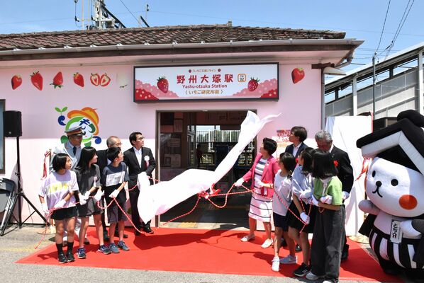 副駅名「いちご研究所前」と入った駅名看板を除幕する関係者と地元児童＝15日午前、栃木市大塚町