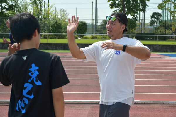 佐野市の地域クラブで中学生に砲丸投げの指導をする吉真さん（右）＝清酒開華スタジアム