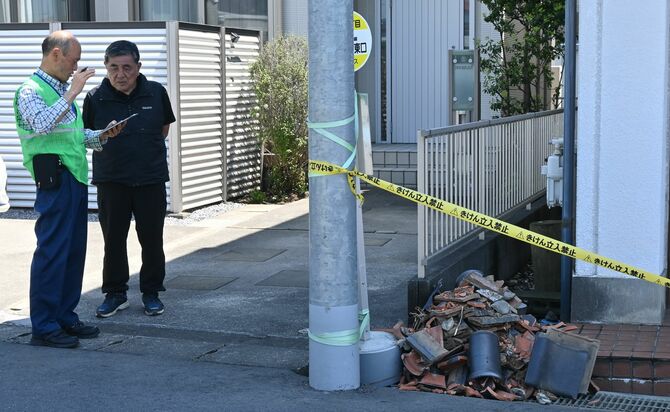 屋根瓦が落ちた現場で調査する宇都宮地方気象台の職員（左）＝２日午前10時40分、宇都宮市雀の宮５丁目