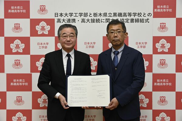 協定書にサインした吉永校長(右)と根本学部長