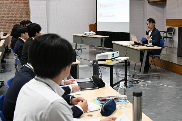 小澤社長（右）の話に耳を傾ける行員たち＝12日午前、宇都宮市