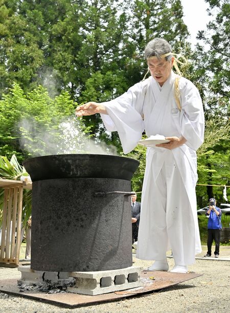 大釜の熱湯を塩で清める神職＝15日午後11時40分、日光市清滝１丁目