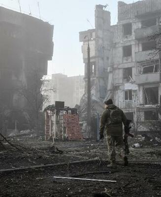 　ロシア軍の攻撃を受けた住宅近くを歩くウクライナ兵＝３月、ウクライナ南部ザポリージャ州オリヒウ（ロイター＝共同）