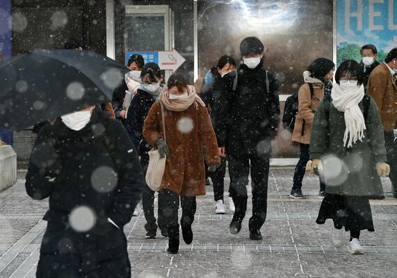 雪が降る中、肩をすくめて通勤通学する人たち＝25日午前７時25分、宇都宮市川向町