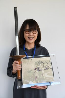 母校に展示されている栃の葉大会のトーチと自身の写真を手にする相吉沢さん＝19日午後、県盲学校