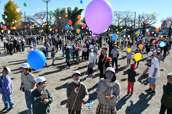風船を大空に飛ばす児童