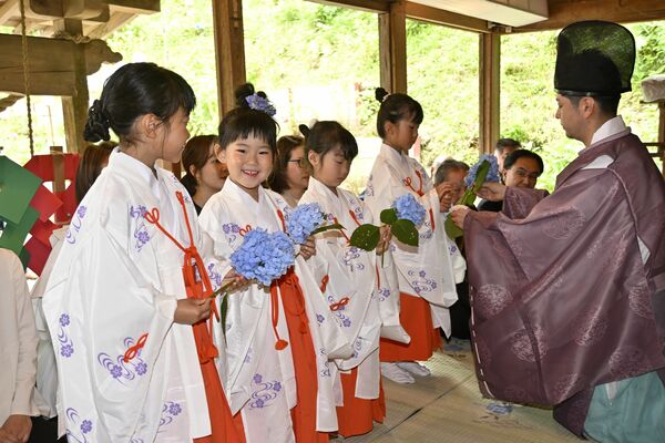 神職からアジサイを受け取る稚児たち