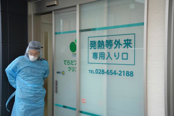発熱などがある患者専用の入口前で、診察の準備をする寺田院長＝16日午後、宇都宮市雀の宮５丁目