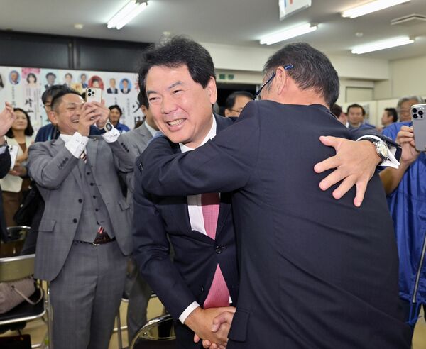 ６選を確実にし、支持者と握手する佐藤栄一氏（左）＝17日午後７時10分、宇都宮市不動前１丁目