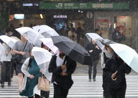 　台風6号の影響による強い風雨の中、新宿駅前を行き交う人たち＝6月3日午前7時40分ごろ
