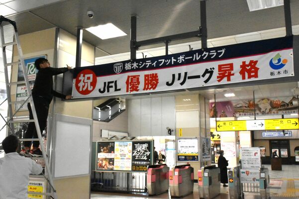 改札口に横断幕を掲出する市職員＝25日午前、東武栃木駅