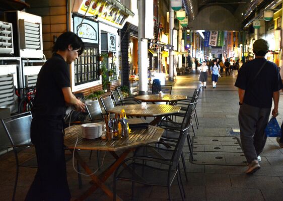 オープンカフェ事業の終了時間となり、屋外の飲食スペースを片付ける飲食店のスタッフ＝７月中旬、宇都宮市江野町