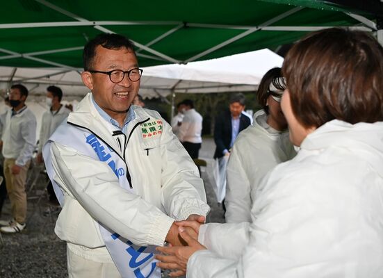無投票で４選を決め、支持者と握手する星野光利氏（左）＝18日午後６時、上三川町しらさぎ１丁目