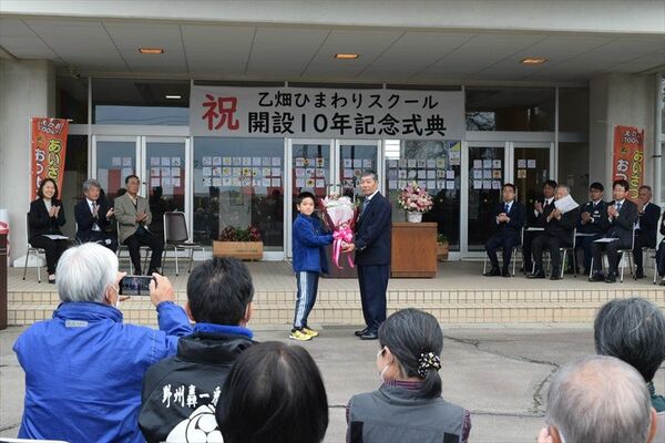 児童から花束を受け取る市村会長（中央右）