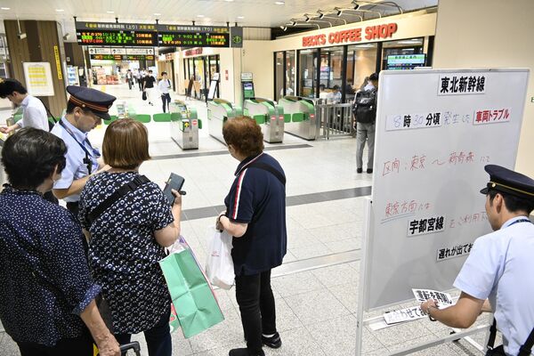 新幹線の改札前で駅員に状況を確認する利用客ら＝19日正午、ＪＲ宇都宮駅