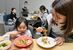 取材班が開設した子ども食堂「ほうぷけん」で焼きそばを頬張る親子＝10日午後６時55分、宇都宮市曲師町