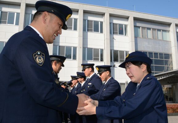 涙ながらに教官と握手する卒業生（手前右）＝２４日午後、宇都宮市若草２丁目