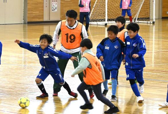 小学生たちとミニサッカーを楽しむ松元さん（中央奥）