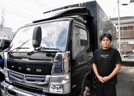 　運送で使うトラックの前に立つ「トランプ」の矢作和徳社長＝埼玉県川口市