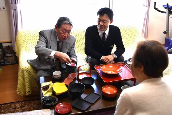 顧客宅で商品を紹介する岡垣会長（左）＝宇都宮市