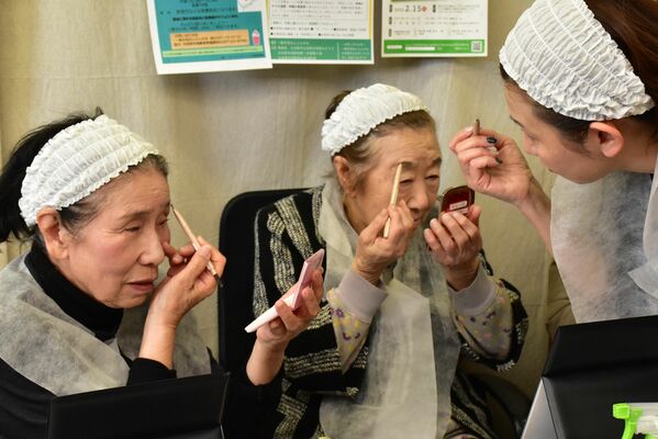 資生堂担当者（右）のアドバイスを受け、お化粧する参加者