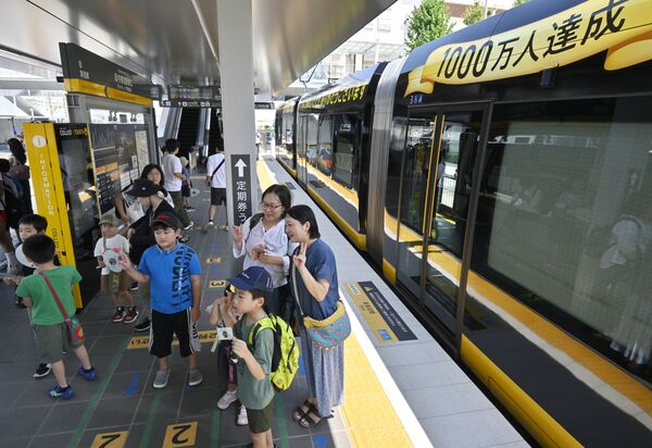 利用者1千万人達成を記念したラッピング車両の前でポーズする親子連れ=23日午前10時55分、宇都宮市宮みらい
