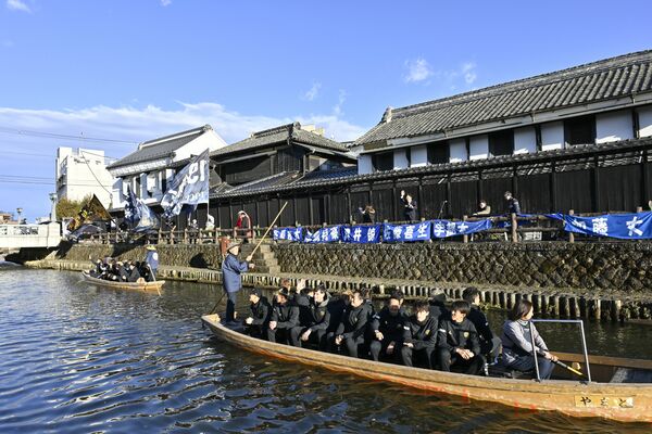 蔵が並ぶ巴波川で船上パレードする栃木シティの選手ら＝11日午後３時15分、栃木市湊町