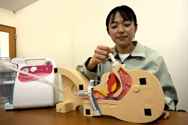 シミュレーターの鼻腔にスプタバキューマーを押し当て痰の吸引を実演する担当者＝栃木市