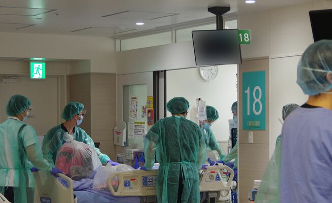 感染対策をして緊急入院患者を集中治療室に入れる職員＝２０２１年１月、下野市薬師寺（自治医大付属病院提供、画像は一部加工しています）