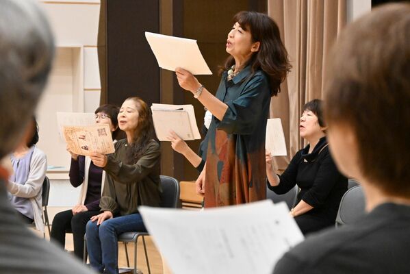 参加者と一緒に朗読する鵜飼さん（中央）