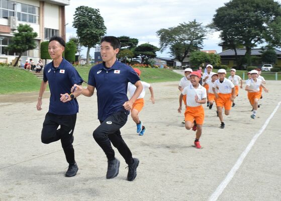児童と競走する唐澤選手（左から２人目）と小林さん（左）