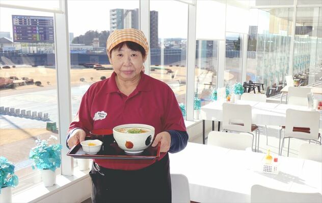 バンクを背景に立つ相田店長