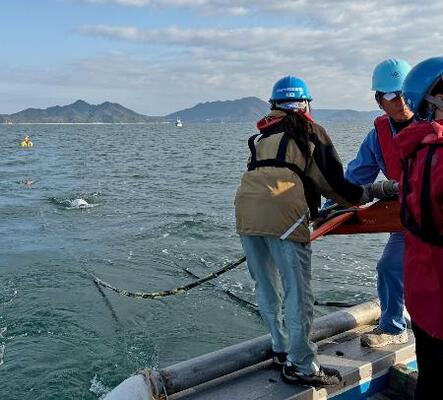 愛媛県上島町の沖合で、海面に探査装置を延ばす産総研の研究員ら=2025年11月(産総研提供)