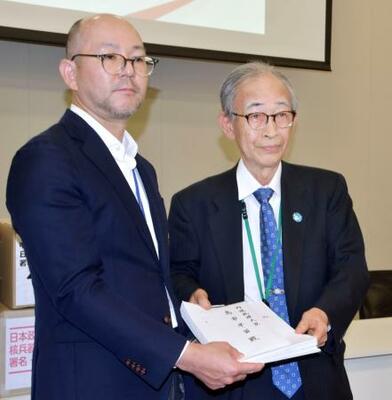 核兵器禁止条約への参加を求める首相宛ての要請書を外務省の松本恭典軍縮不拡散・科学部審議官(左)に手渡す被団協事務局長の浜住治郎さん=19日午後、国会