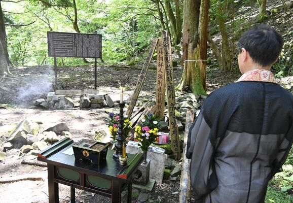 新しくなった銘板（奥）と慰霊碑の前で営まれた追悼式＝27日午前、日光市足尾町