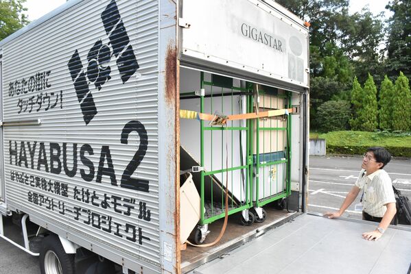 16日夕に会場近くに到着した、はやぶさ２の実物大模型を積んだトラック。石川さんは興味深そうにのぞき込んだ