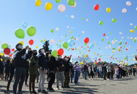 風船を空へ放つ児童ら