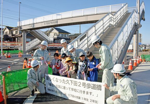 歩道橋架け替えを祝いテープカットする児童たち