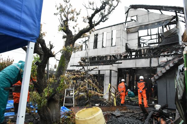 全焼した住宅を調べる県警の捜査員と消防隊員＝22日午前10時５分、真岡市島