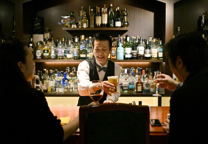 客と乾杯する秋元さん。人と人とをつなぐ店でありたいと願う＝４月20日午後７時20分、那須塩原市末広町、広瀬華撮影