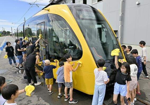 ぞうきんを使ってＬＲＴを拭き上げる参加者たち＝12日午前９時50分、宇都宮市下平出町