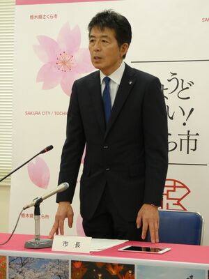 会見の冒頭、立って所信表明を行う中村市長