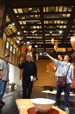 モビールや陶芸などの展示作品。出品者と語り合うサトウさん（中央）